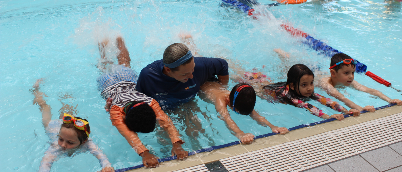 Child swimming underwater with swim teacher or instructor